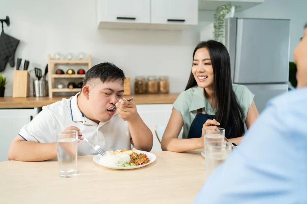 Disabled man eating dinner at home with two carers
